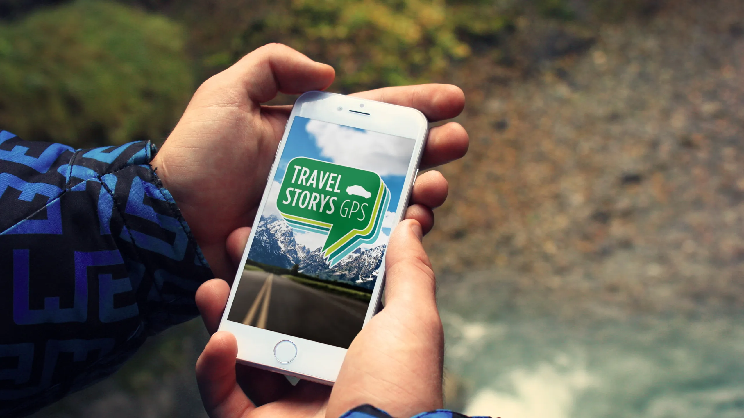View of a hand holding a phone with the travel storys logo on the screen